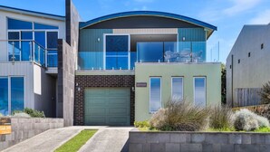 A modern two-story house with a green garage, a balcony with outdoor furniture, and a sign indicating "Moyan." - Offering breathtaking views of South Beach (Port Fairy)