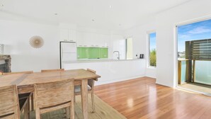 A modern kitchen with white cabinets, a green countertop, and a large window. - Offering breathtaking views of South Beach (Port Fairy)