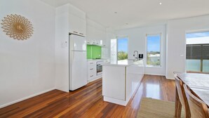 A modern kitchen with white cabinetry, a green countertop, and a wooden floor. - Offering breathtaking views of South Beach (Port Fairy)