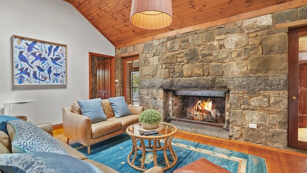 A cozy living room with a stone fireplace, a leather sofa, and a blue abstract painting. - A bluestone cottage in the heart of Port Fairy (Port Fairy)