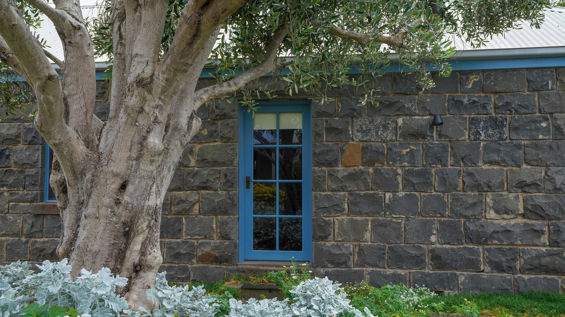 A stone building with a large tree in front.