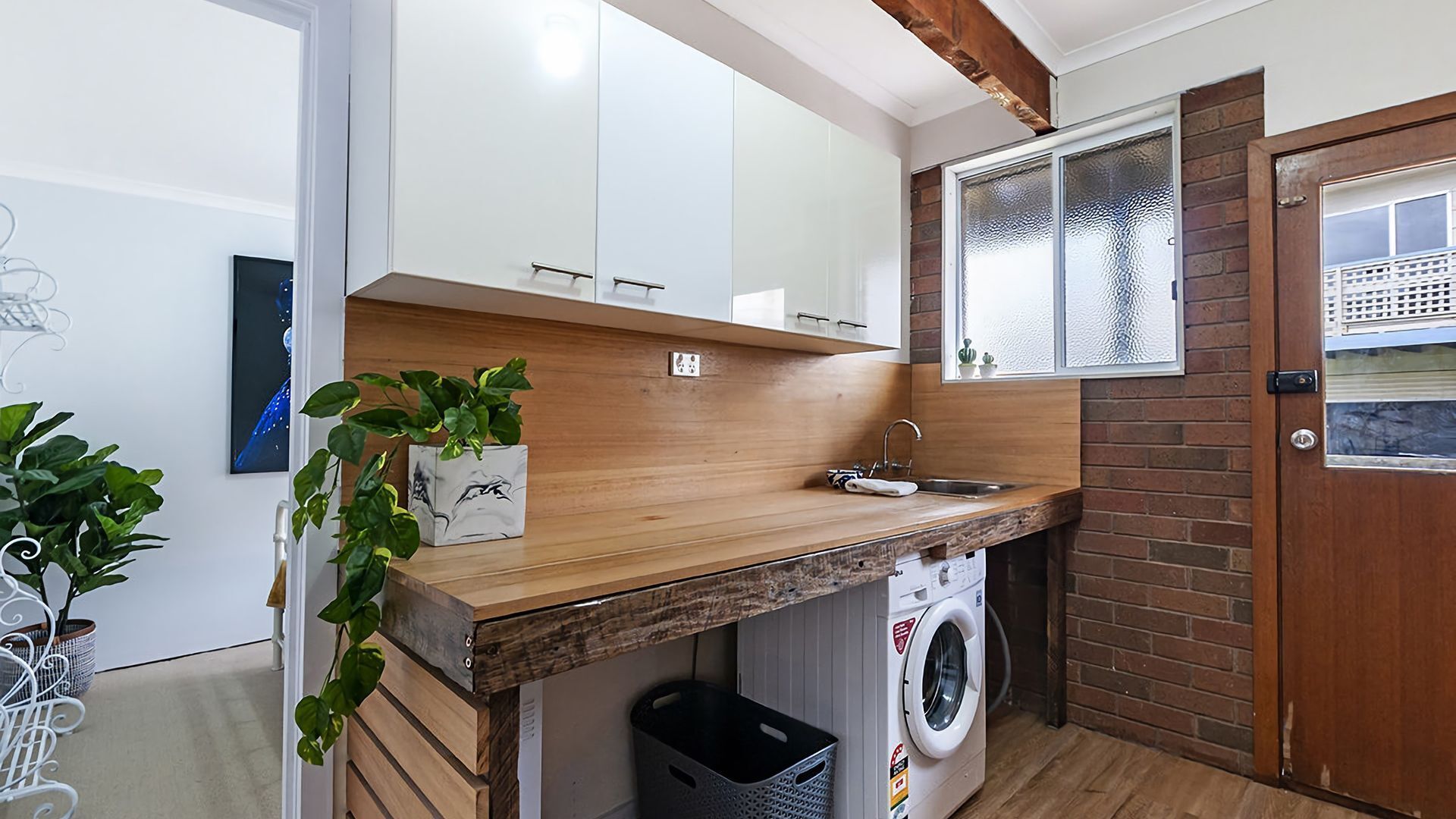 Una cocina funcional con encimeras de madera, lavadora integrada y un ventanal con vistas.