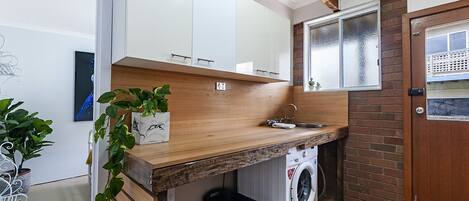 Una cocina funcional con encimeras de madera, lavadora integrada y un ventanal con vistas.