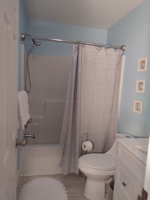 A bathroom with a shower, toilet, and vanity.