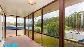 Una habitación con ventanas amplias, piso alfombrado y vista a una carretera y árboles.