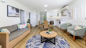 Een moderne woonkamer met een bank, twee fauteuils, een salontafel en een eethoek met een tafel en stoelen.
