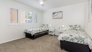 Een slaapkamer met twee bedden, een bureau en een plafondventilator.