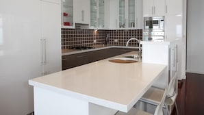 Una cocina moderna con armarios blancos, una isla central y un lavamanos de acero inoxidable.