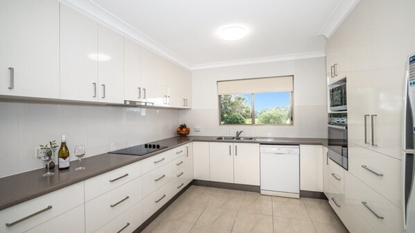 A modern kitchen with white cabinetry, a built-in oven, and a dishwasher.