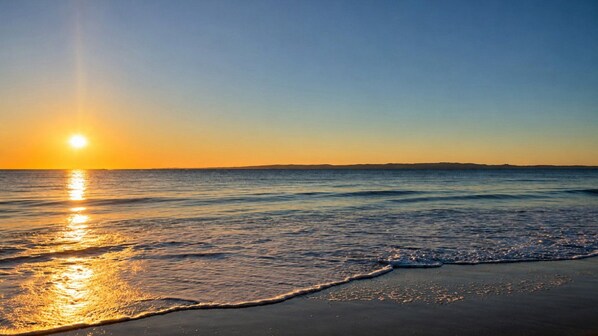 A beach with a sunset over the ocean.