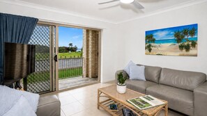 A living room with a sofa, a coffee table with a plant, and a painting of a beach scene.