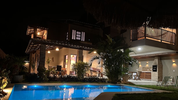 Une maison moderne dotée d’une piscine, d’un espace salon extérieur et d’un patio bien éclairé.