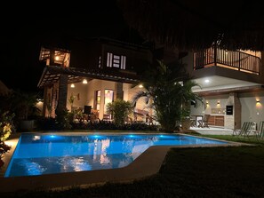 Une maison moderne dotée d’une piscine, d’un espace salon extérieur et d’un patio bien éclairé.