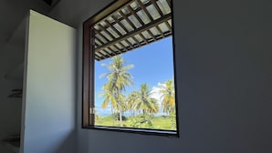Une chambre avec une fenêtre donnant sur des palmiers et un ciel dégagé.