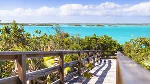 Une promenade en bois qui mène à une eau turquoise sous un ciel dégagé.
