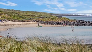 Une plage avec une promenade en bois, un rivage rocheux et des personnes pratiquant diverses activités.