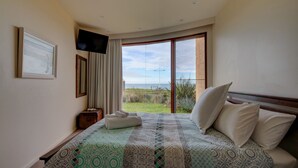 Camera d'albergo con un letto grande, una televisione, una finestra vista spiaggia e un quadro appeso al muro.