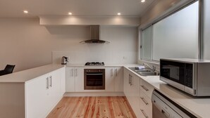 Eine moderne Küche mit weißen Schränken, einem Backofen, einem Gasherd, einer Mikrowelle und einem großen Fenster.