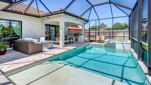 Una piscina esterna coperta con zona solarium, barbecue e area vetrata.