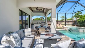 Patio esterno con piscina, barbecue e zona salotto con cuscini.