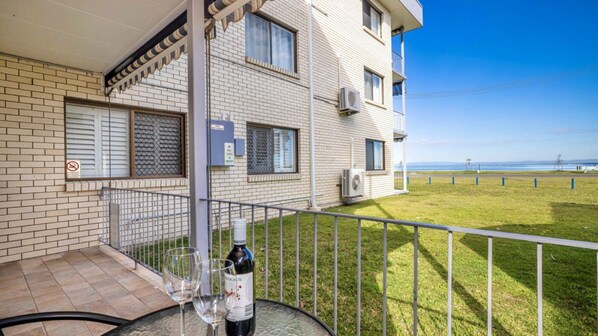 A balcony with a table, a bottle of wine, and two glasses.