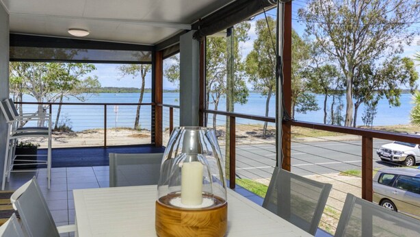 Un comedor con mesa, sillas y vistas a un lago a través de amplios ventanales.
