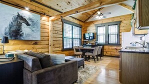 Un intérieur de chalet chaleureux comprenant un coin repas, un canapé et une cuisine.