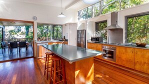 Une cuisine moderne dotée d’un grand îlot central, d’appareils électroménagers en acier inoxydable et d’armoires en bois.