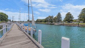 Une jetée en bois qui mène à une marina où sont amarrés des voiliers.