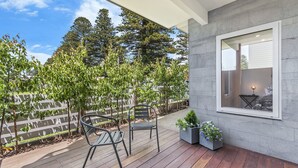 Une terrasse avec deux chaises, une petite table et des plantes en pot.