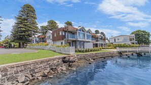 Une propriété située au bord de l’eau, avec des maisons modernes, un mur de soutènement en pierre et un quai.