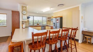 A modern kitchen with a central island, wooden chairs, and a dining table. - Spacious Unit Overlooking Moreton Bay (WOORIM)