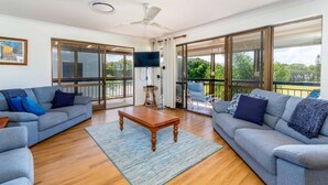 A spacious living room with two grey sofas, a wooden coffee table, and a large TV screen. - Spacious Unit Overlooking Moreton Bay (WOORIM)
