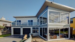 Ein modernes, zweistöckiges Haus mit Balkon, großen Fenstern und Garage.