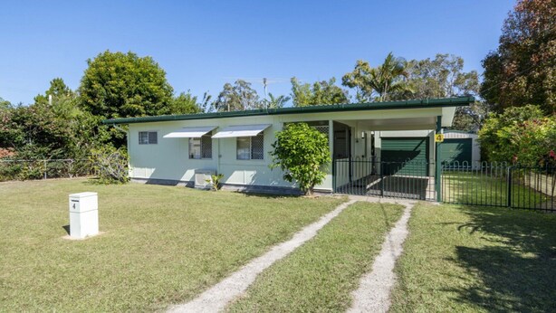 Una casa a un piano con tetto verde, un portico anteriore e un garage.