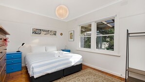 A bedroom with a bed, two nightstands, a dresser, a window with a view, and wall art. - A quaint artistic cottage for all seasons (PORT FAIRY)