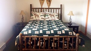 Una cama con un edredón estampado, dos adornos en la pared y dos lámparas de noche.