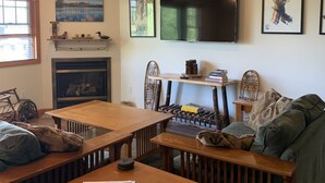 Una sala de estar acogedora con chimenea, un televisor montado en la pared y una zona de estar confortable con sofá y sillones.