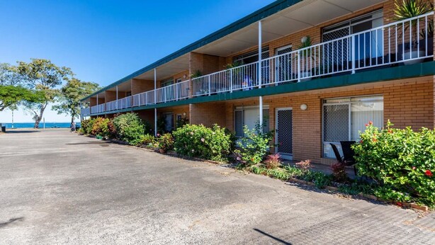 A motel with a two-story structure, a covered parking area, and a view of the sea. - Bribie Waters On Welsby (BONGAREE)