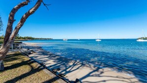 A beach with a clear blue sky, calm sea, and a few sailboats. - Bribie Waters On Welsby (BONGAREE)