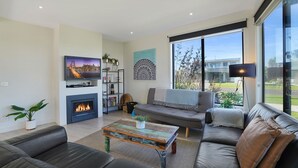 A modern living room with a fireplace, a large TV, and a comfortable seating area with a view of the outside.