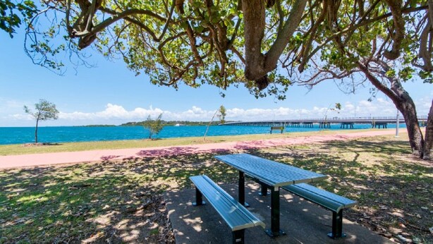 A park with a bench, a walking path, and a view of the sea and a pier. - Bongaree Retreat With Room For The Boat (BONGAREE)