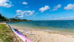 A beach with a canoe on the sand, clear blue water, and a distant island. - Bongaree Retreat With Room For The Boat (BONGAREE)