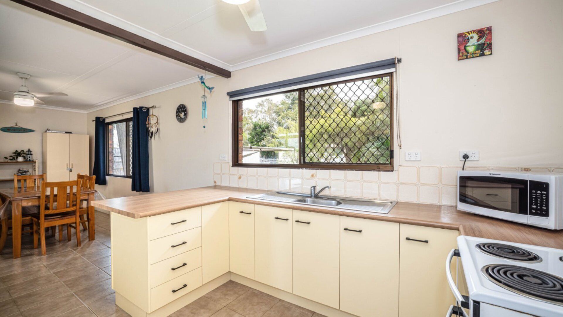 A kitchen with a stove, microwave, sink, and wooden chairs.