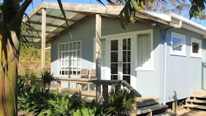 A small, single-story house with a porch and a covered outdoor seating area.
