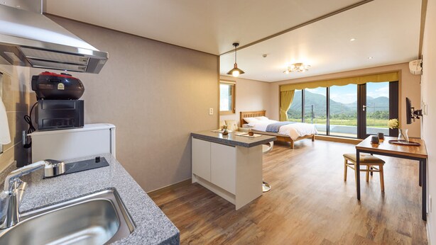 A modern kitchen with a built-in stove, a sink, and a dining area with a table and chairs. - Gyeongpoen Pension (Gangneung)
