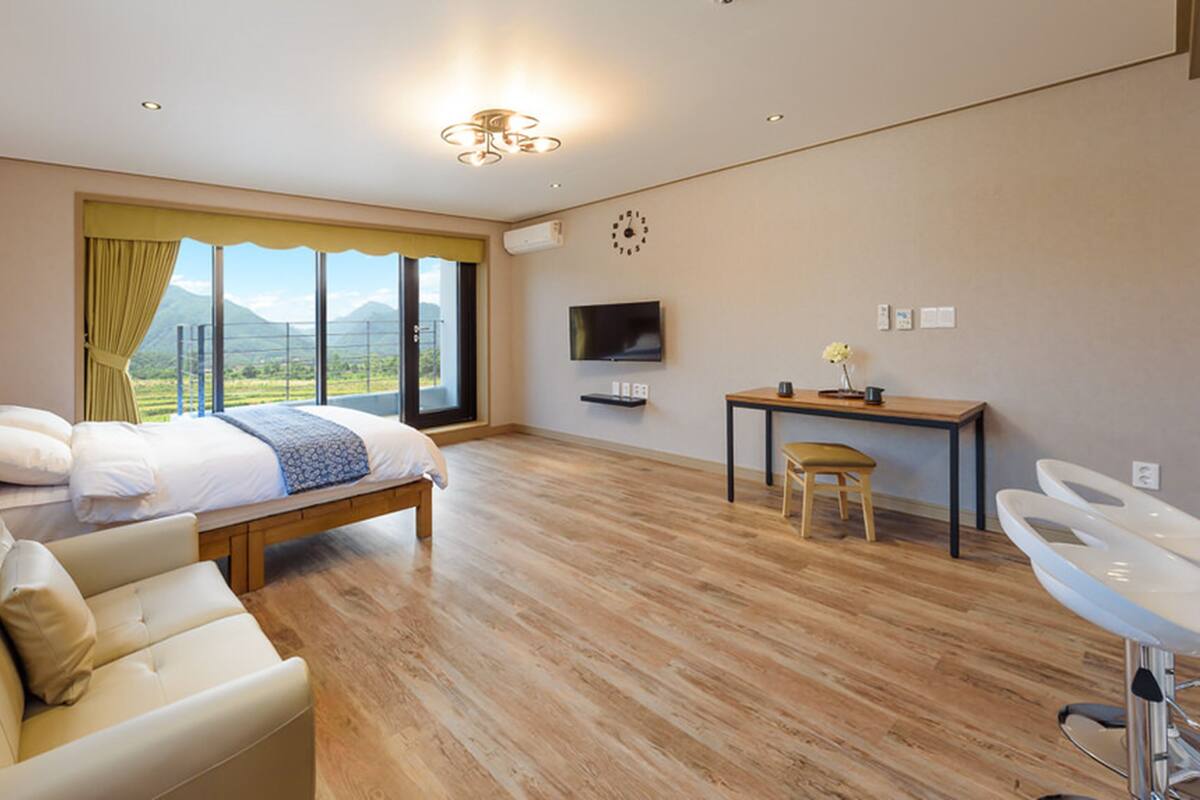 Ein modernes Schlafzimmer mit Bett, einer Couch, einem Schreibtisch und einem Fernseher.