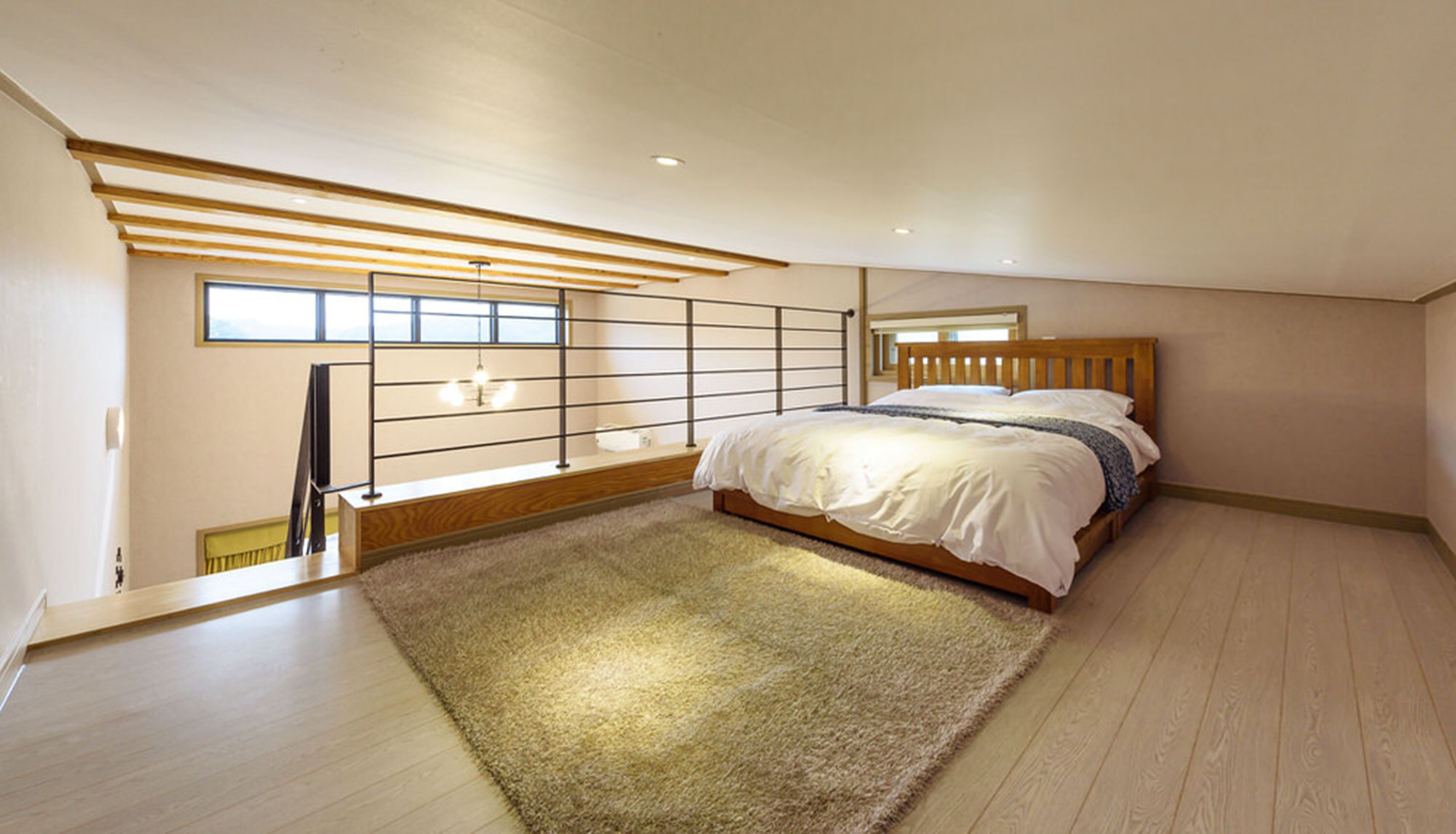 A bedroom with a wooden bed, a large window, and a sloped ceiling.