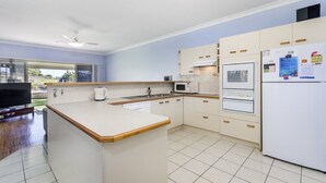 Een moderne keuken met een centraal eiland, witte apparaten en uitzicht op de omgeving.