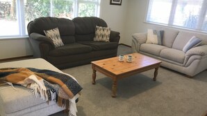 A living room with two sofas, a coffee table, and a blanket on an ottoman.